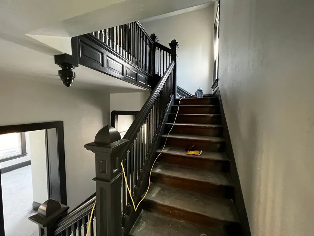 A staircase with a black railing and wooden steps in a house.