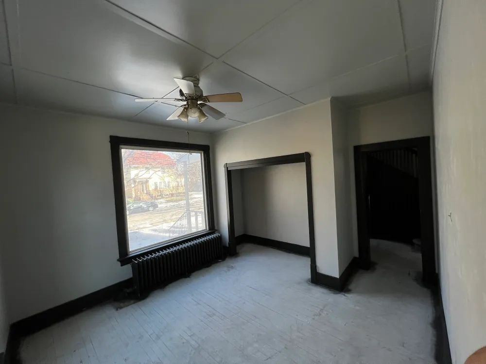 An empty room with a ceiling fan and a window