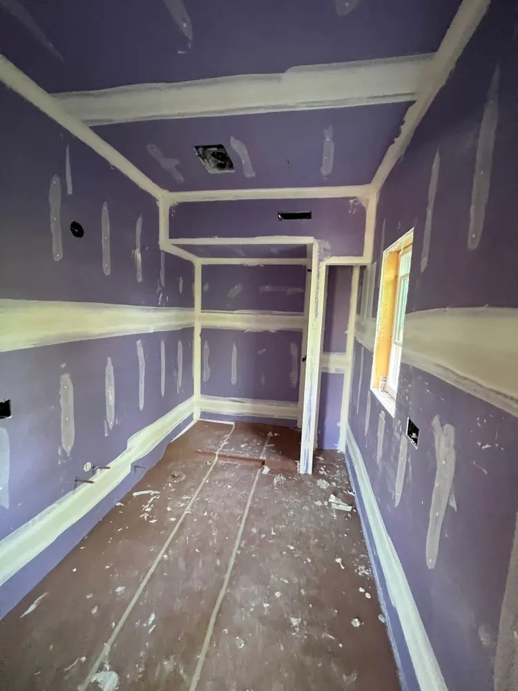 An empty room with purple walls and white trim