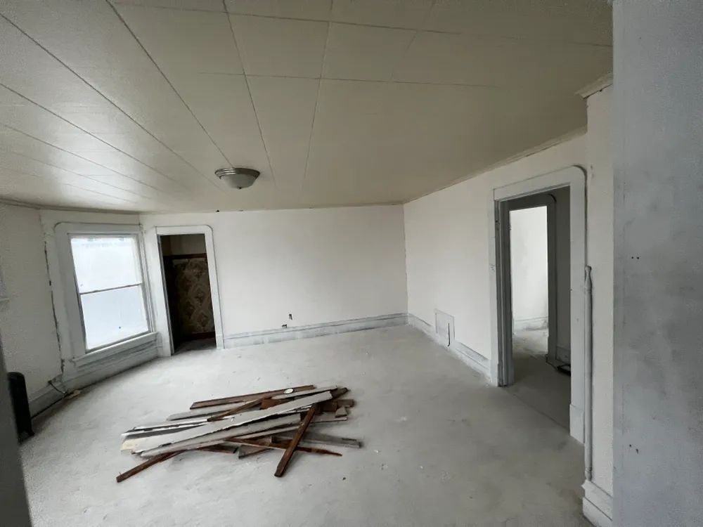 An empty room with a pile of wood on the floor.