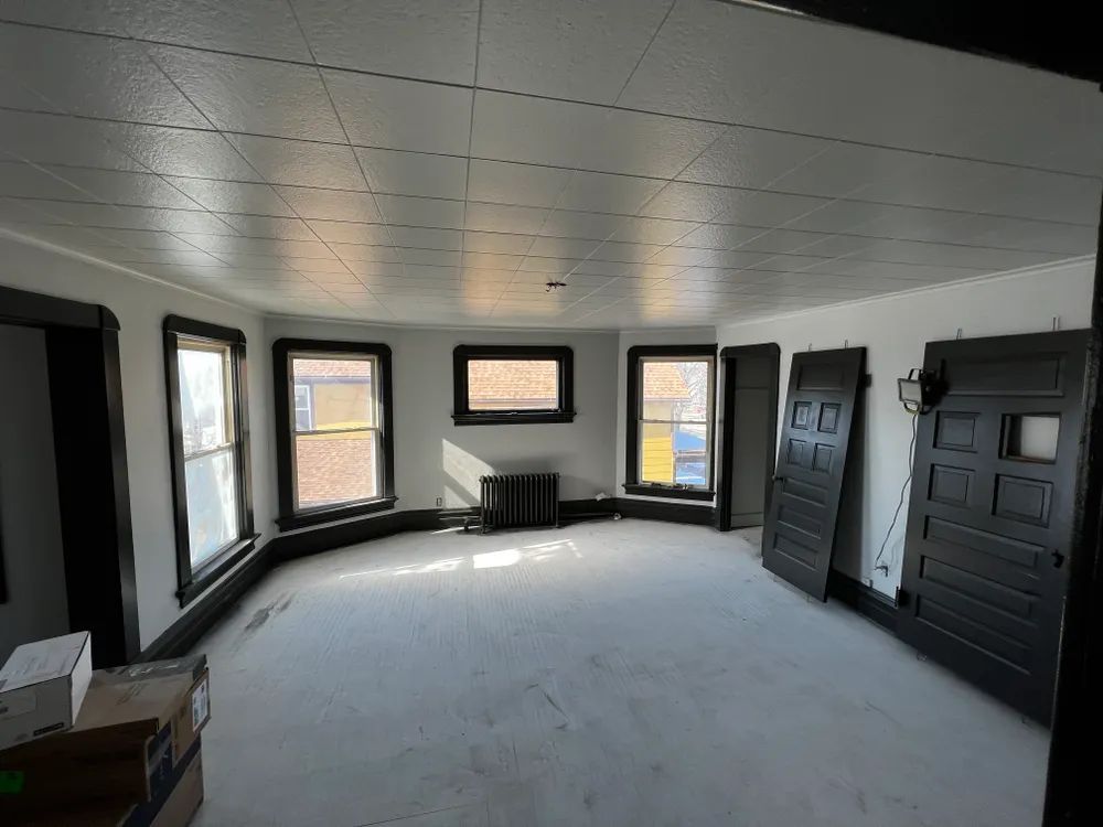 An empty room with white walls and black doors