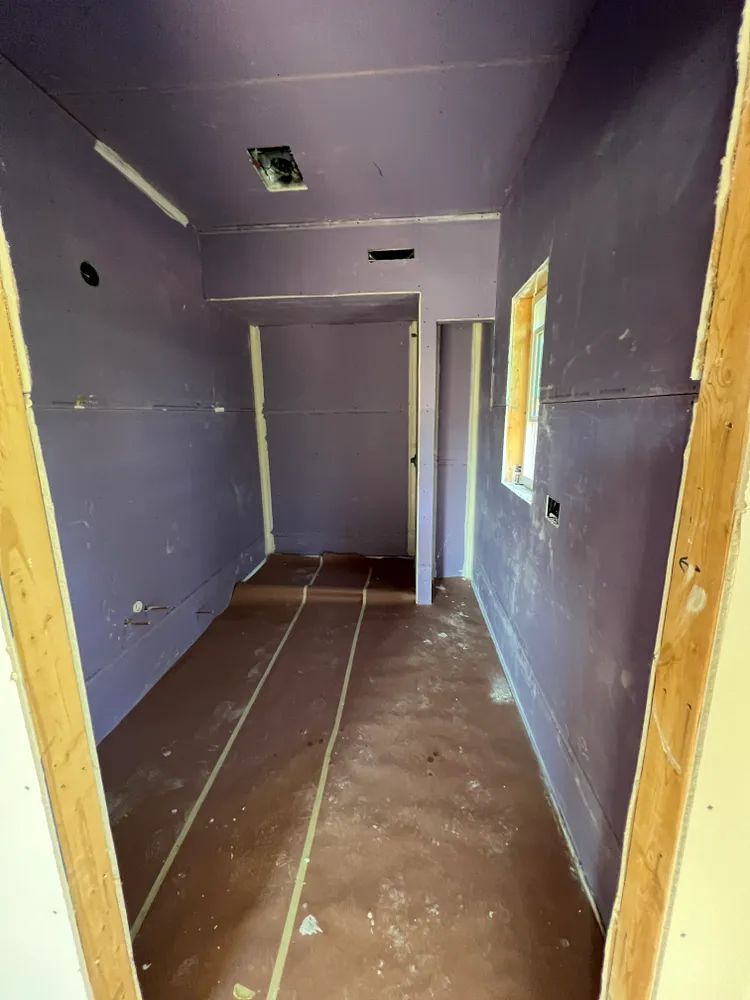 An empty room with purple walls and brown floors