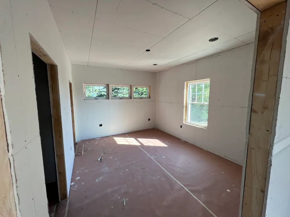 A room with a lot of windows and drywall on the walls.