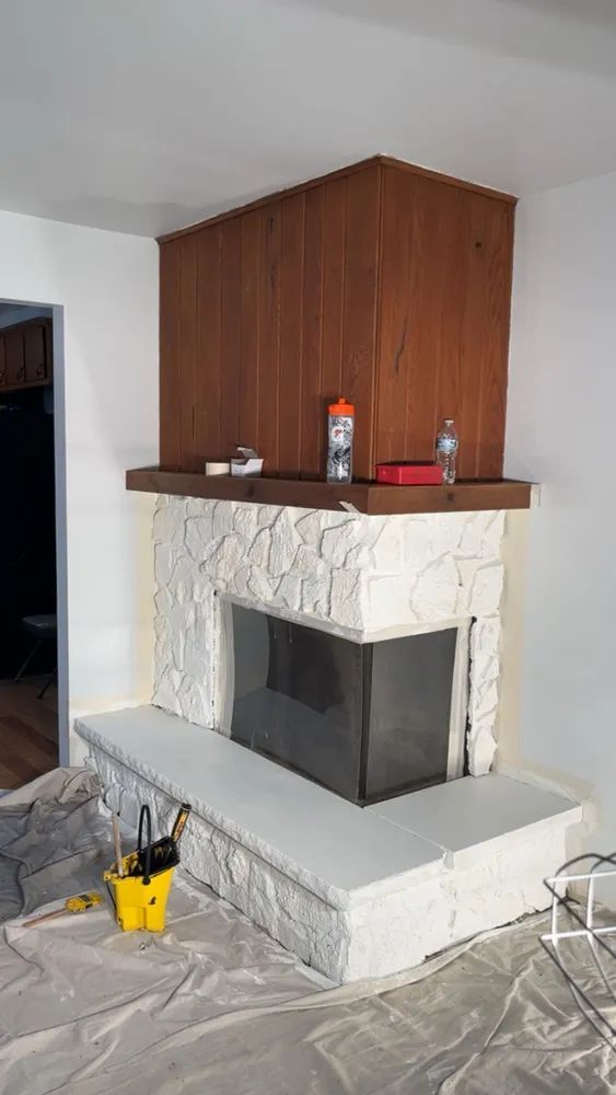 A fireplace is being painted in a living room.