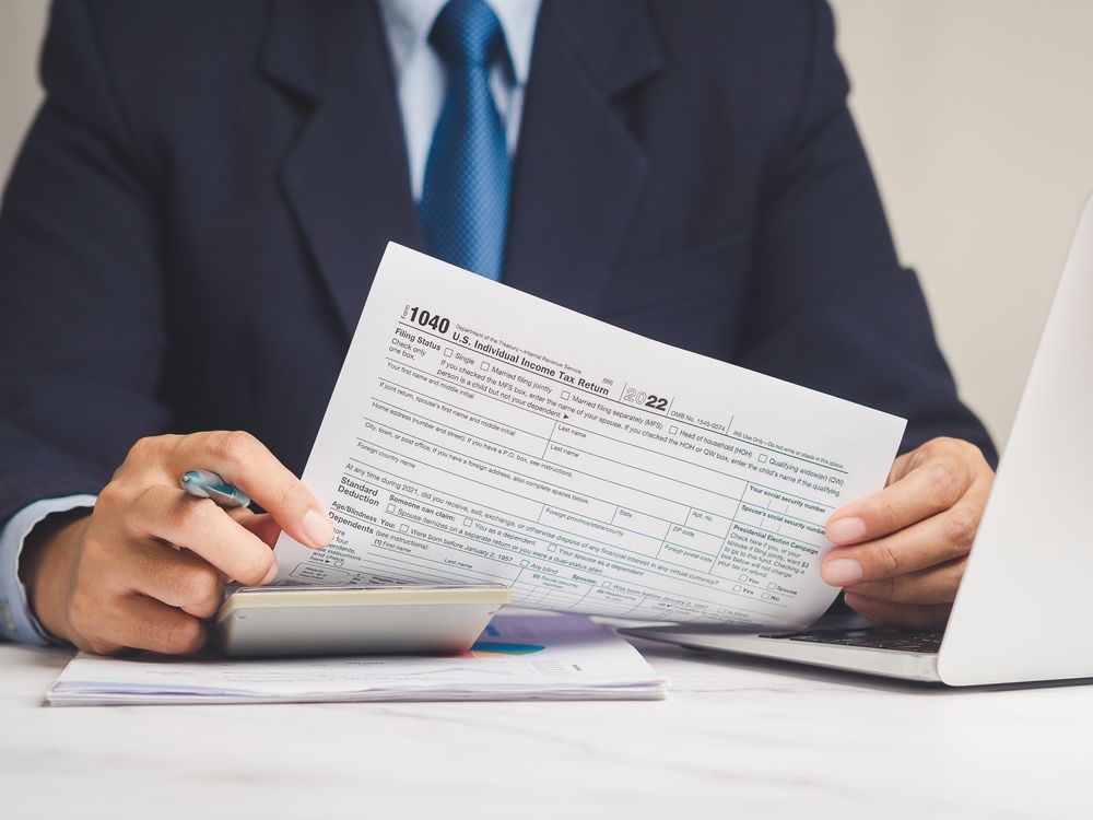 Person in a suit reviewing a document at a desk with a calculator and laptop