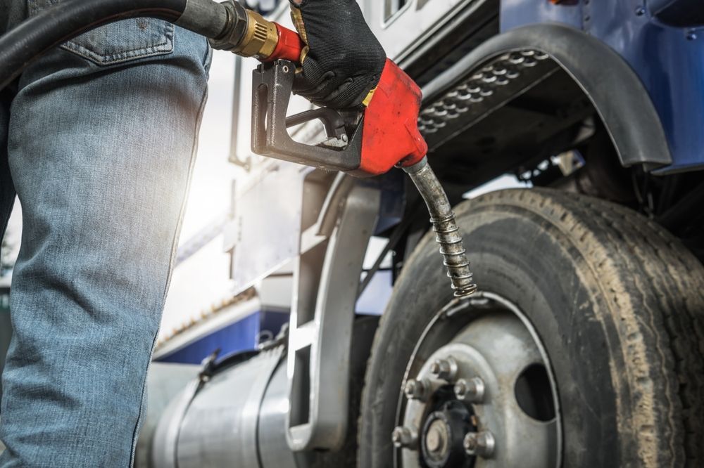 A man is pumping gas into a truck.