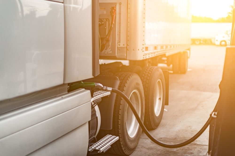 A semi truck is being filled with gas at a gas station.