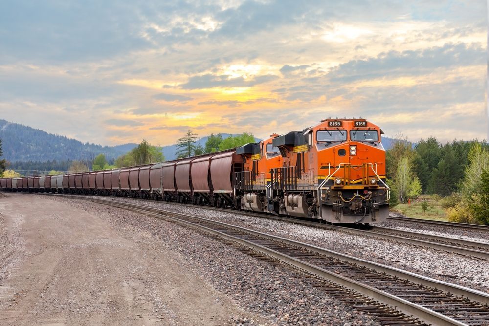 A train is going down the tracks at sunset.