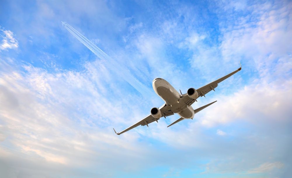 A large passenger jet is flying through a cloudy blue sky.