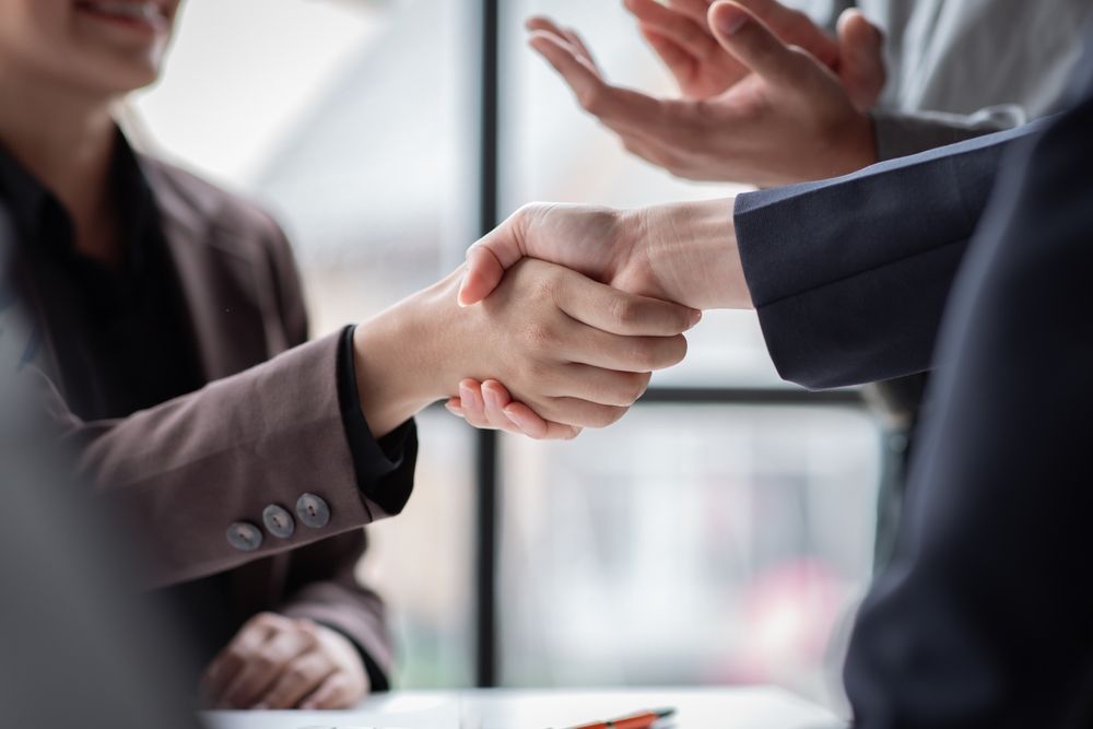 A group of people are shaking hands while sitting at a table.