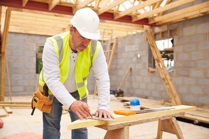 Contractor marking wood for cutting at a residential build site.