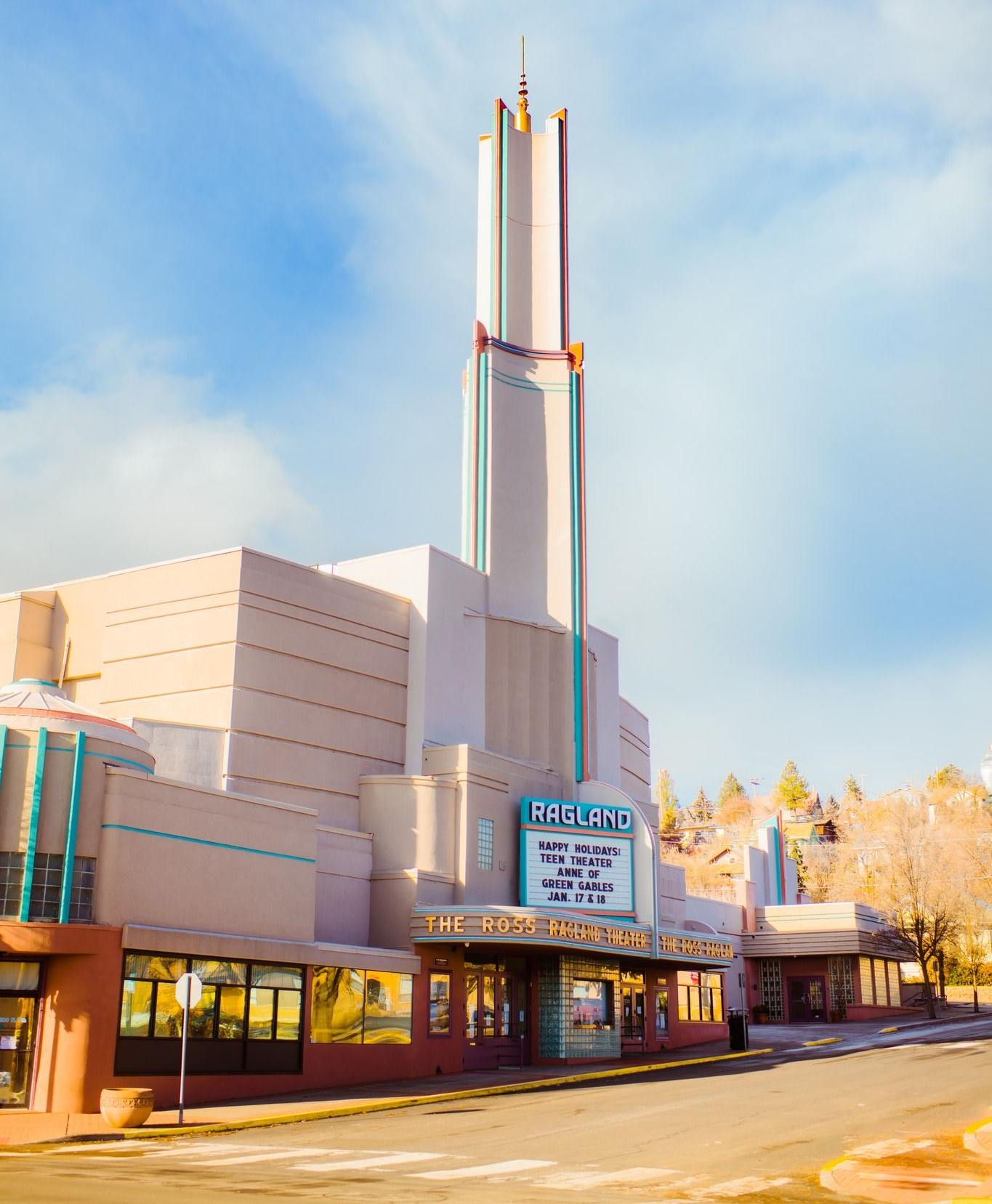 Art Deco theater building with a tall tower, pale colors, and marquee.