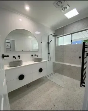Modern bathroom with double vanity, grey concrete-look floors, and walk-in shower, all in shades of white and grey. — Precise Plumbing & Drainage In Conder, ACT