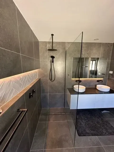 Modern Bathroom With Grey Tiles, Shower, Double Sinks, and a Glass Wall — Precise Plumbing & Drainage In Conder, ACT