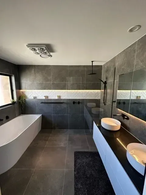 Modern Bathroom With Grey Tiles, White Bathtub, and Black Fixtures — Precise Plumbing & Drainage In Conder, ACT