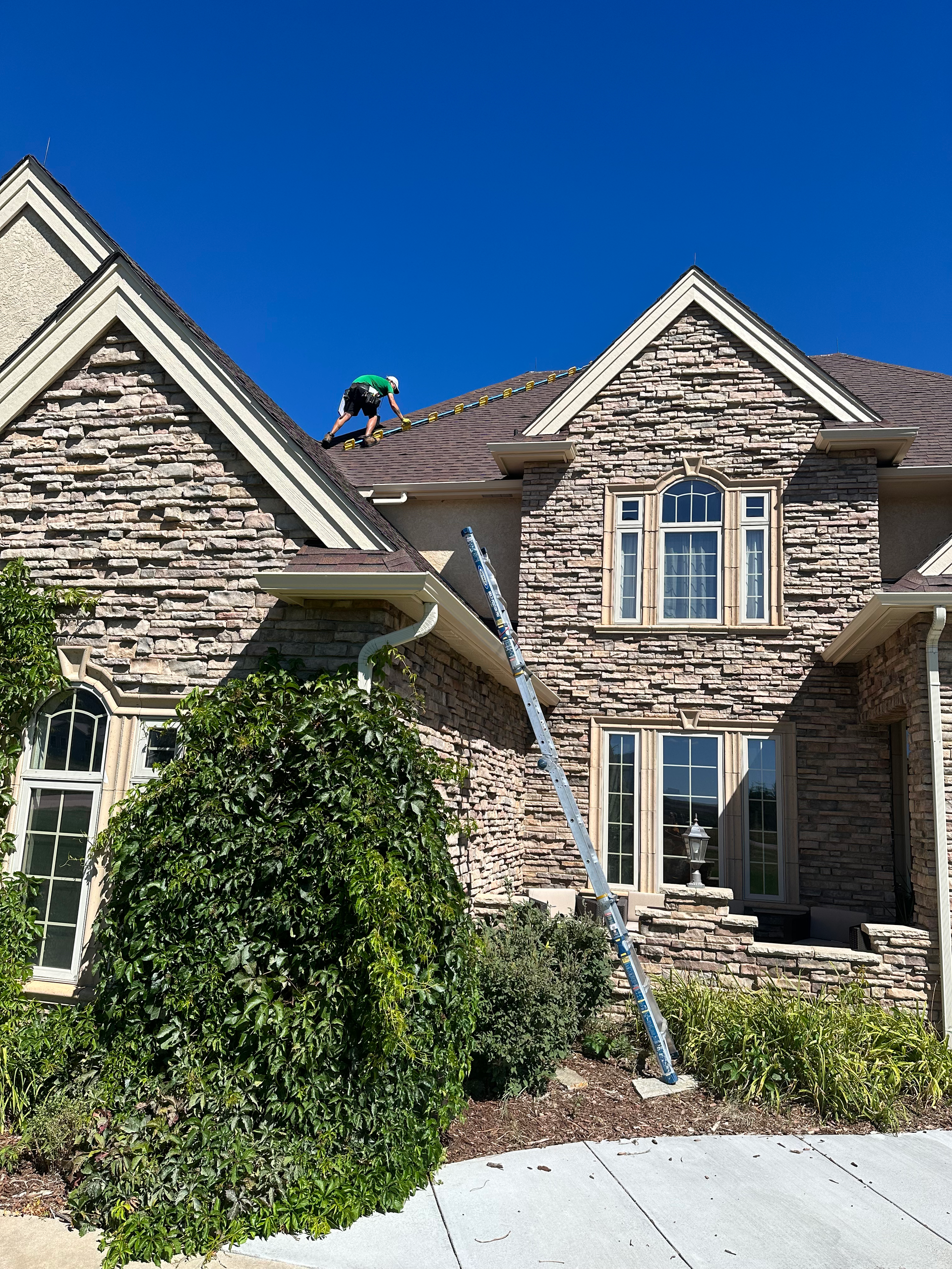 A man is working on the roof of a brick house.