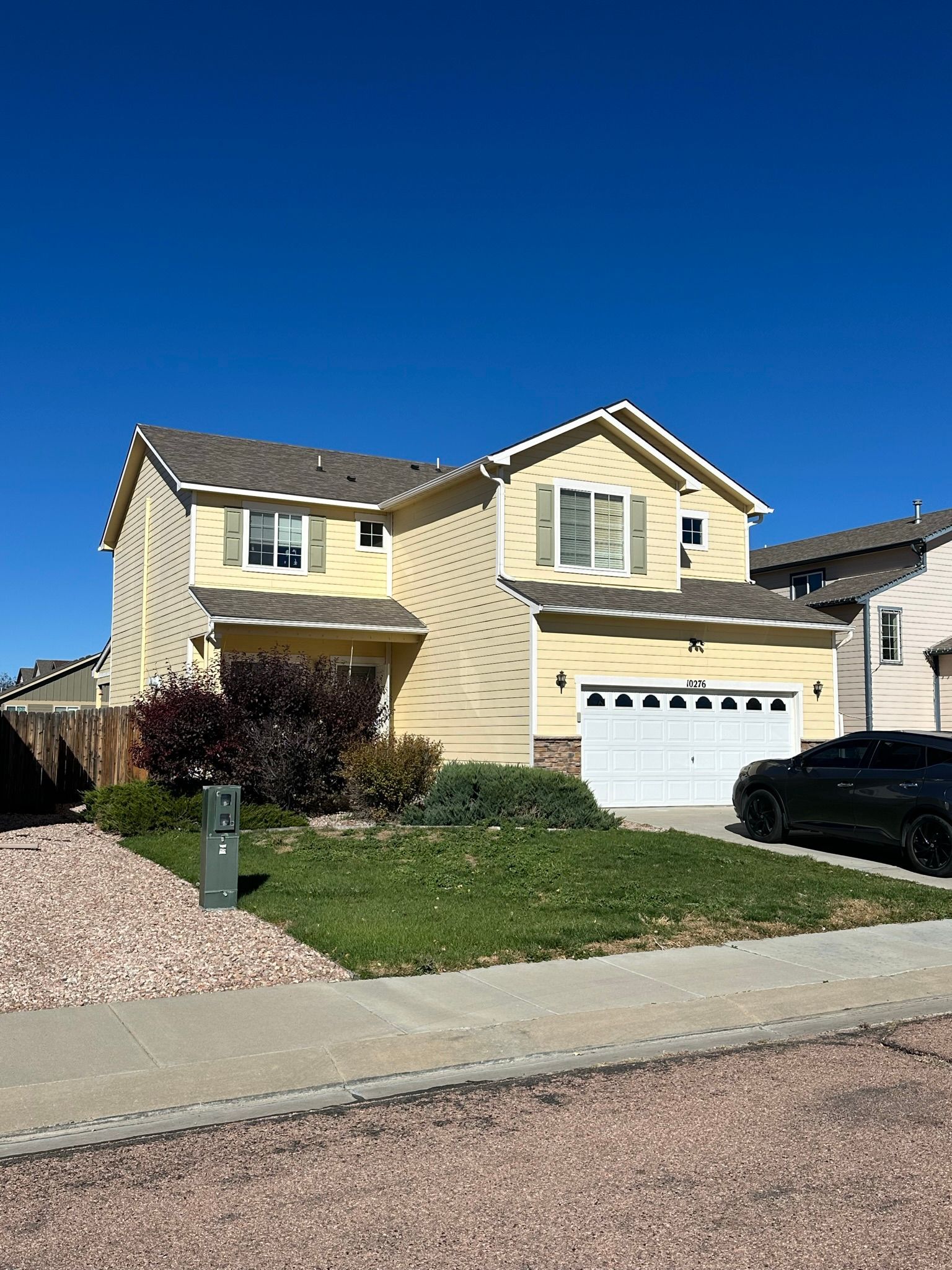 A large yellow house with a car parked in front of it.
