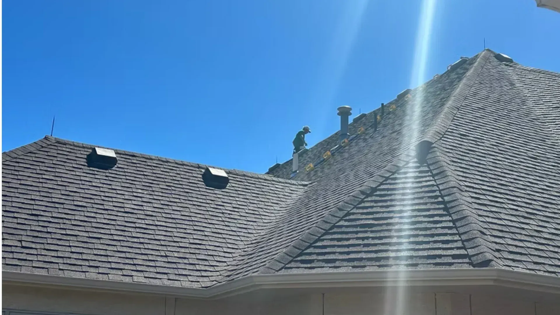 Two men are working on the roof of a house.