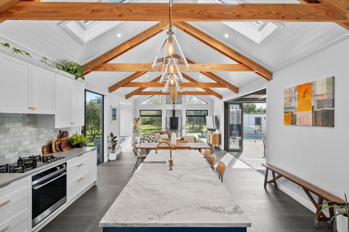 Hallway with wood slat ceiling, potted plants, round mirror, and framed artwork.