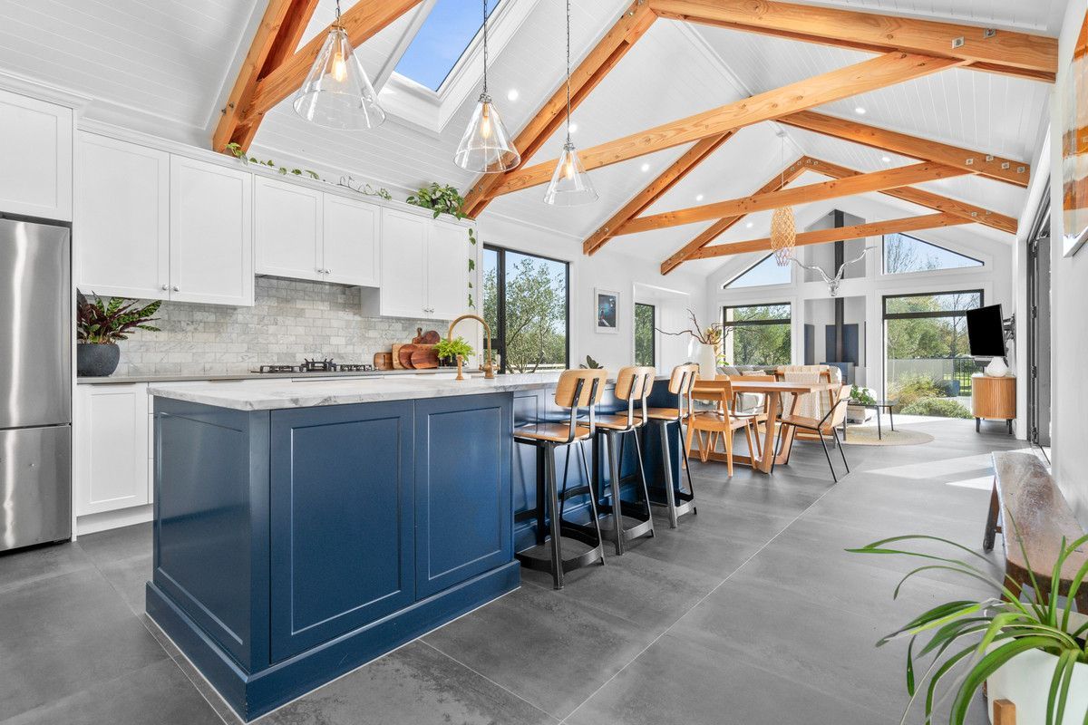 Spacious modern kitchen with blue island, white cabinets, and wooden beams.