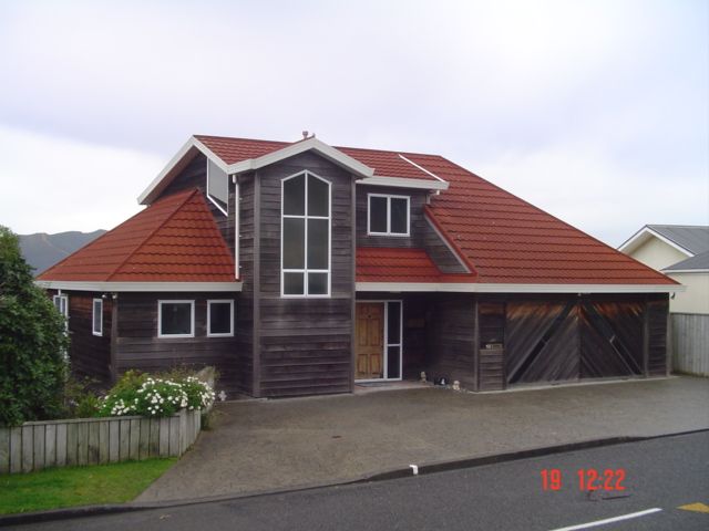 House with red tiled roof, wooden siding, and a two-car garage under an overcast sky.