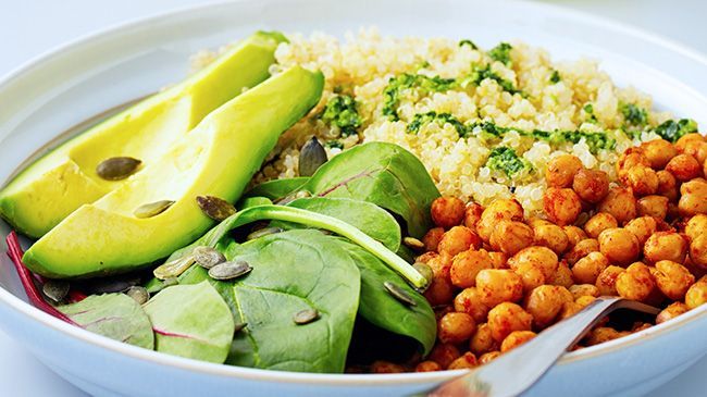 A plate of food with avocado , chickpeas , spinach and rice.
