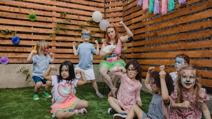 Un grupo de niños están sentados en el césped con las caras pintadas.