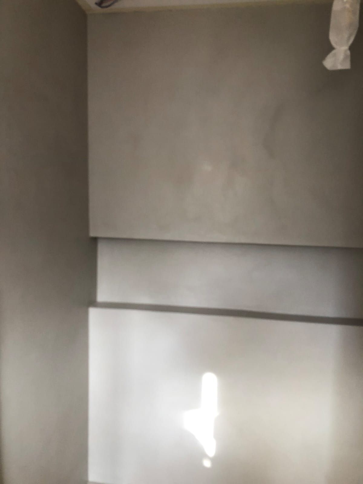 Tre sezioni rettangolari grigie di parete in un angolo. La luce si riflette sulla sezione inferiore.