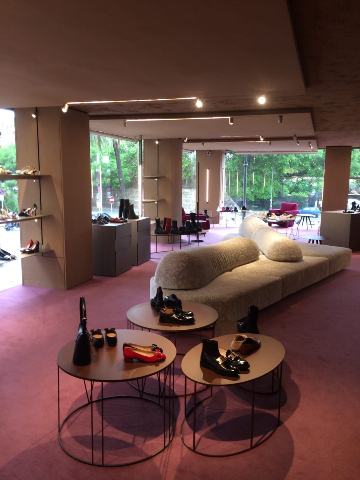 Interno di un negozio di scarpe con moquette rosa, mobili moderni ed espositori di scarpe.