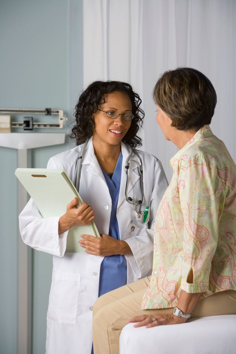 A doctor is talking to a patient while holding a clipboard.