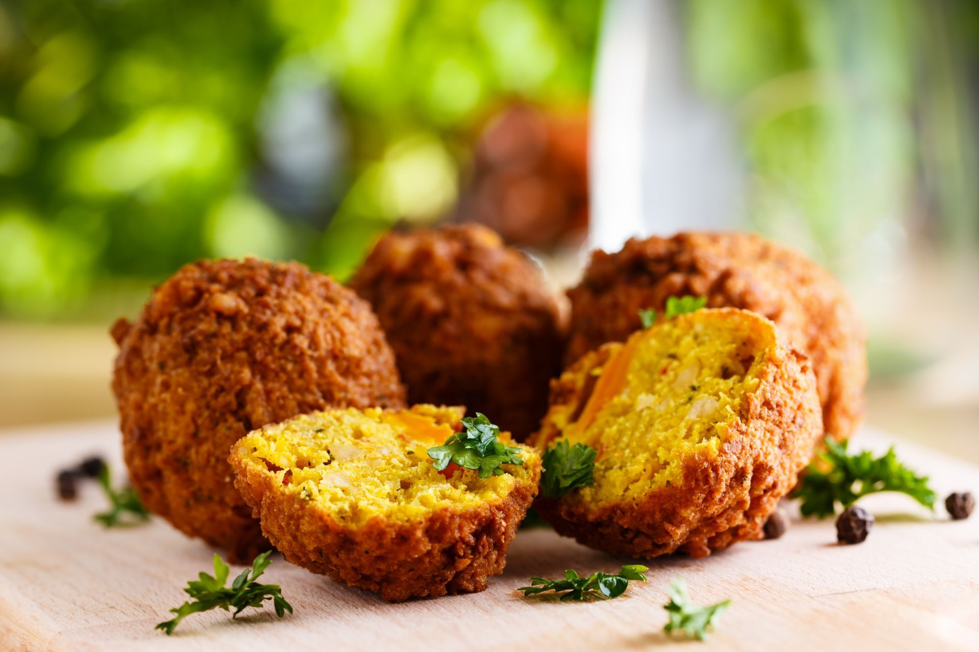 A close up of falafel balls on a wooden cutting board.