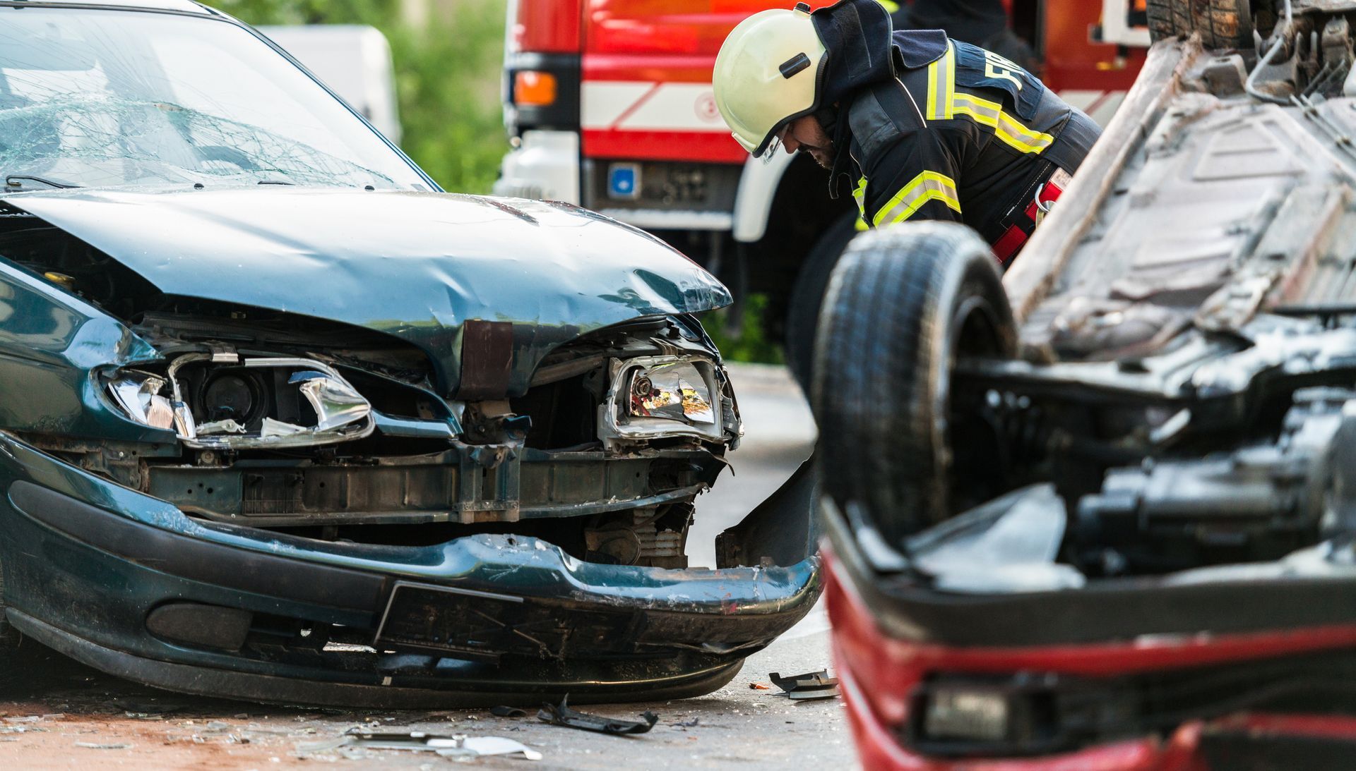 A fireman is working on a car that has been damaged in a car accident.