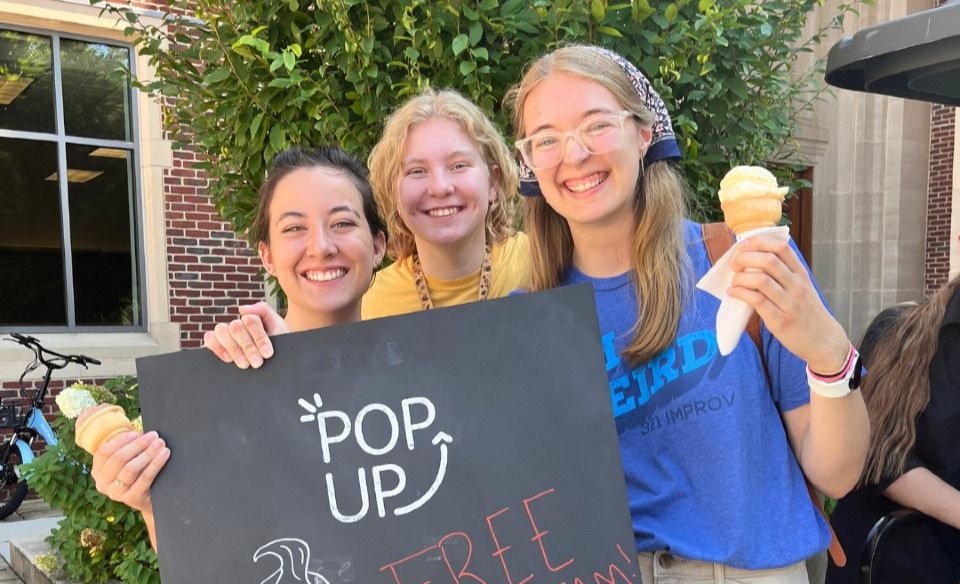 Three young women holding free ice cream cones, posing.