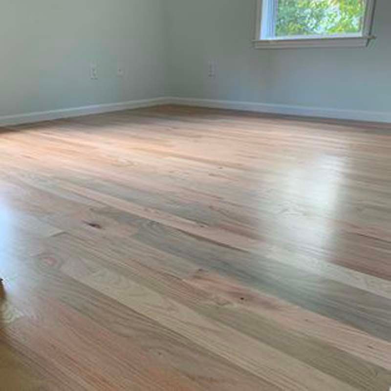 A bedroom with hardwood floors and a window.
