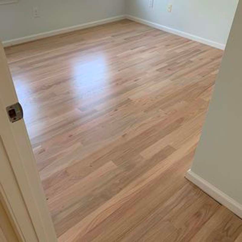 A bedroom with hardwood floors and white walls.