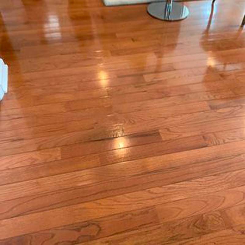 A wooden floor in a living room with a table and chairs.