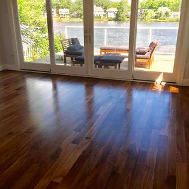 A living room with hardwood floors and sliding glass doors leading to a balcony overlooking a lake.