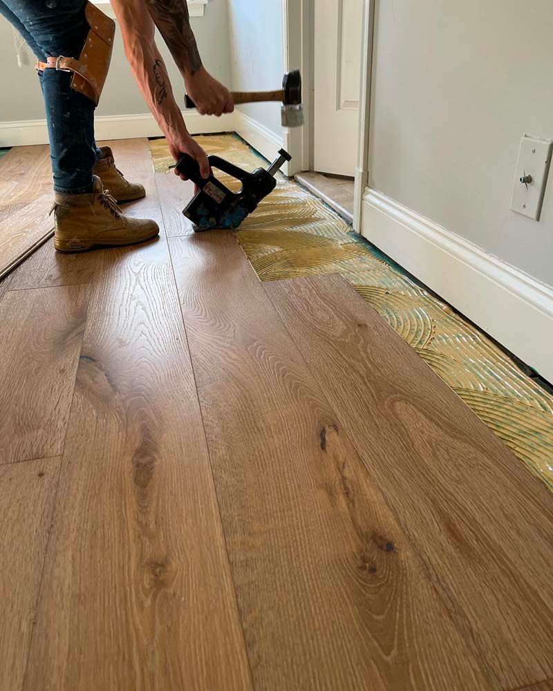 A man is installing a hardwood floor in a room.