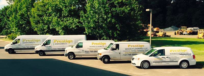 A row of white vans are parked in a parking lot.