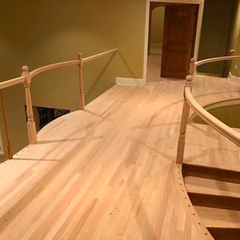 A wooden staircase with a glass railing and a wooden floor in a house.