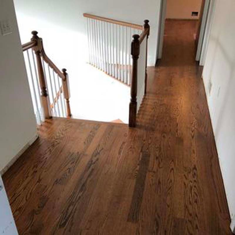 A hallway with hardwood floors and stairs leading up to the second floor.