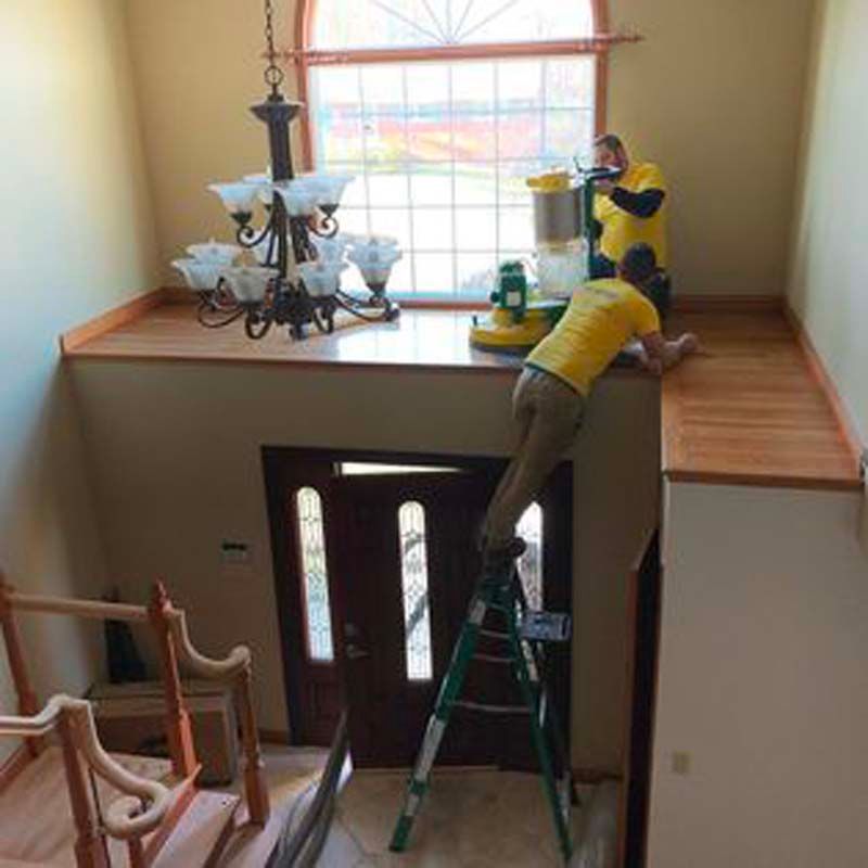 A man is standing on a ladder in a room with a vacuum cleaner.