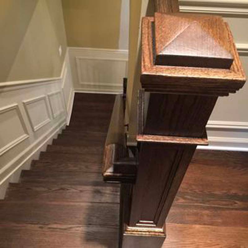 A close up of a wooden railing on a set of stairs.