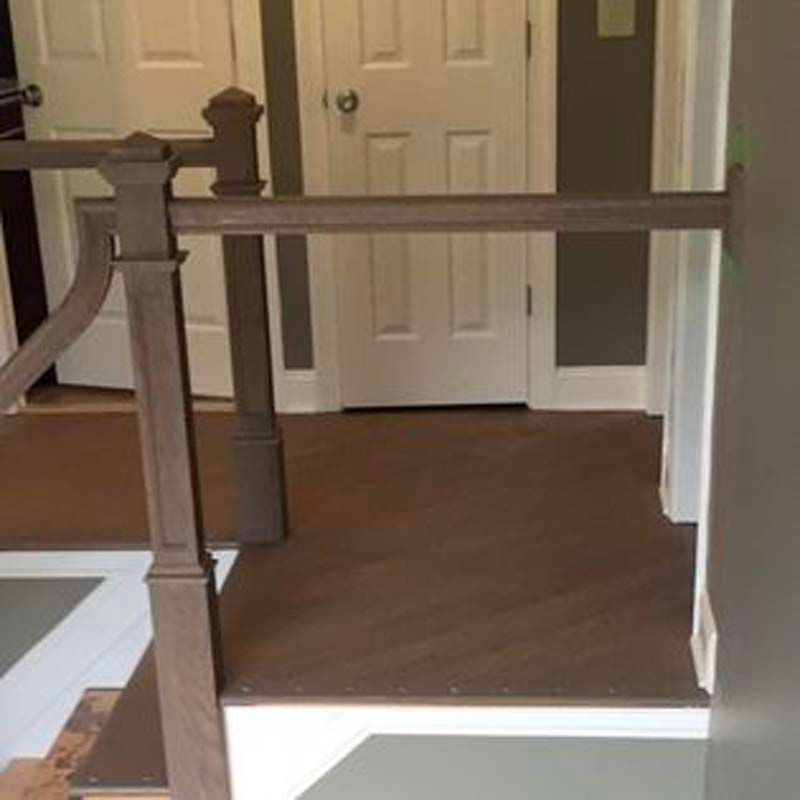 A hallway with stairs and a wooden railing in a house.