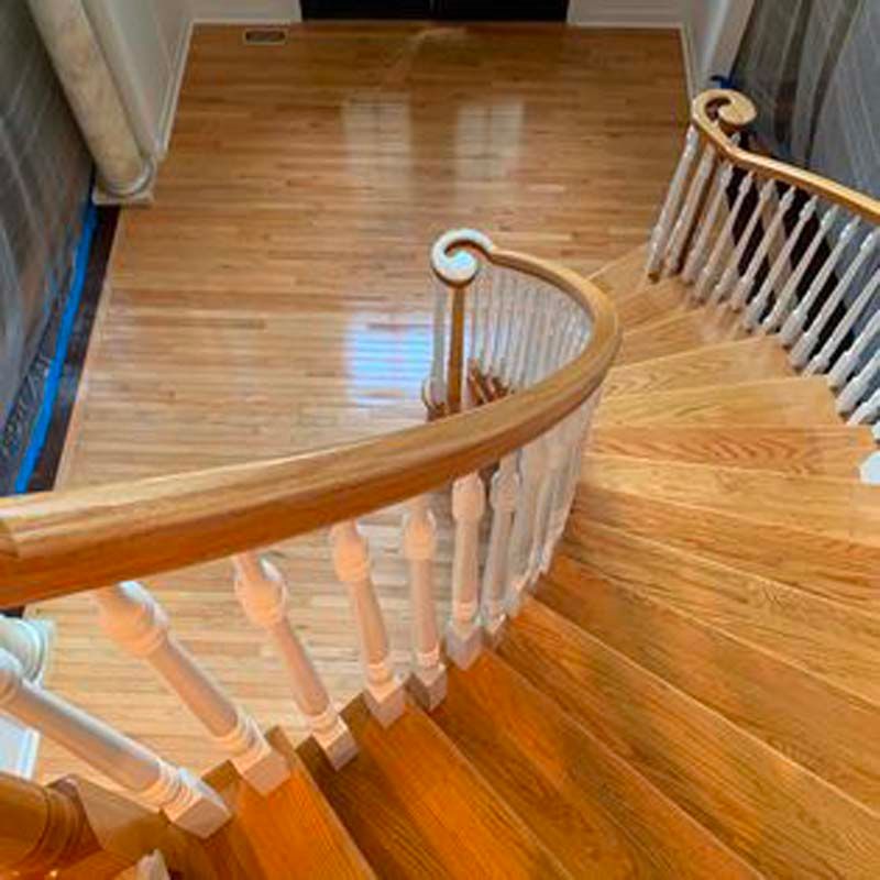 An aerial view of a wooden spiral staircase with a white railing.