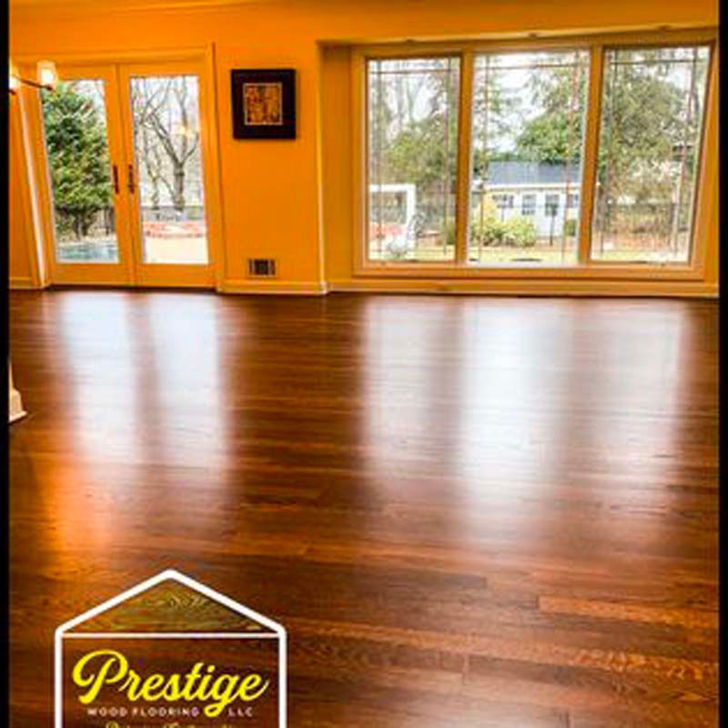 A living room with a wooden floor and lots of windows.
