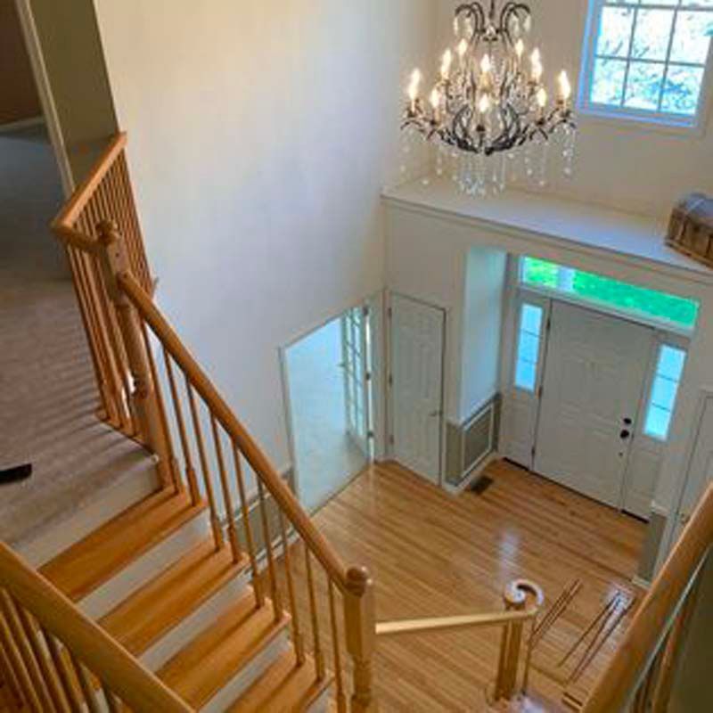 The stairs are made of wood and there is a chandelier hanging from the ceiling.