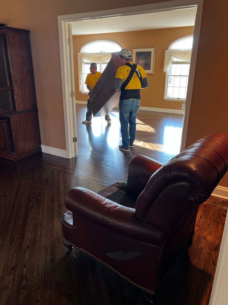 Two men are carrying a large piece of furniture in a living room.