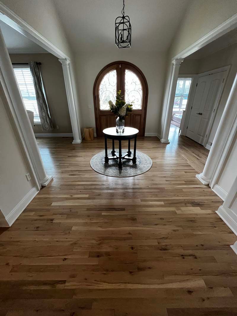 A hallway with hardwood floors and a table in the middle of it.
