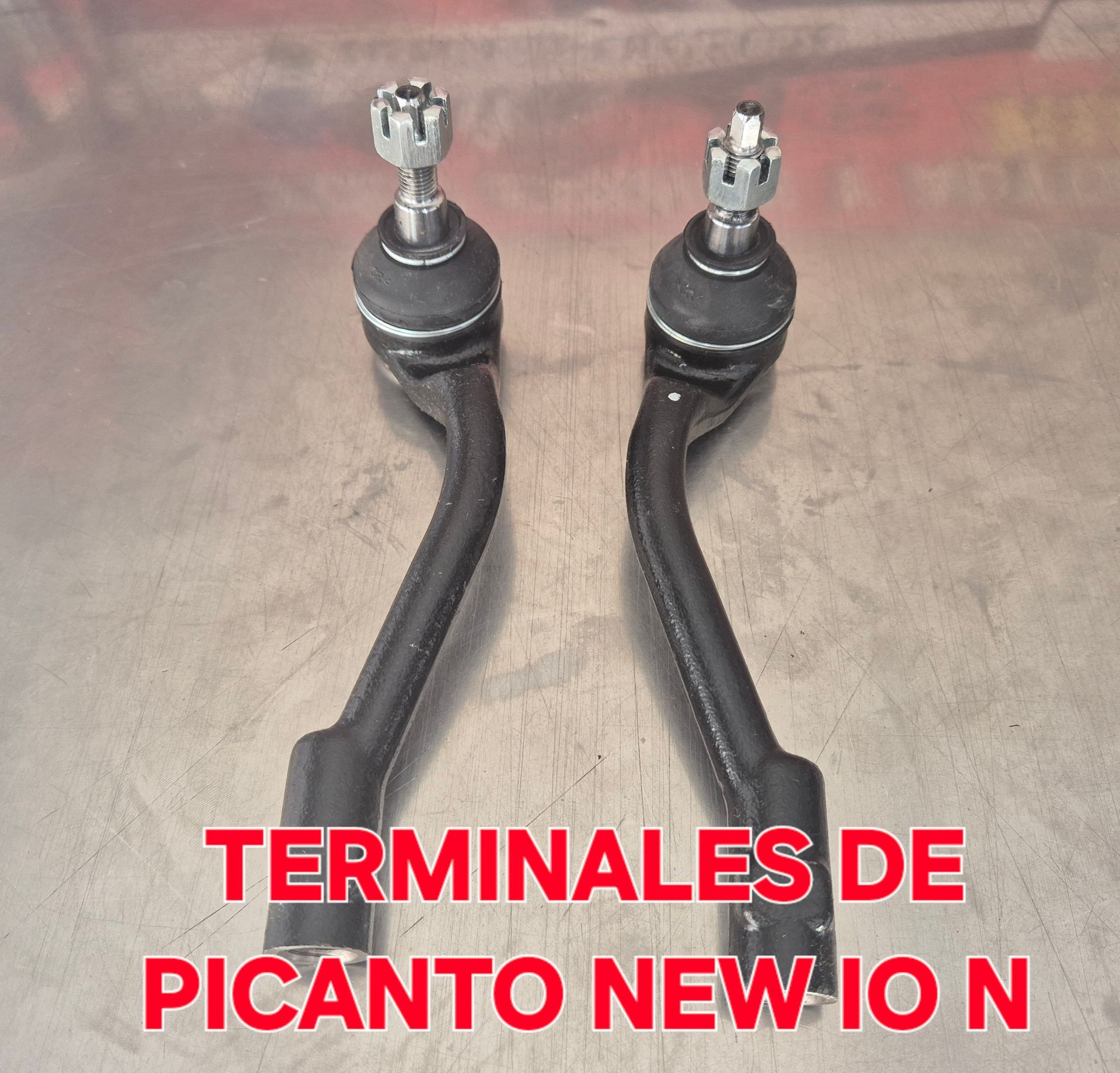 Dos terminales de dirección negros con puntas metálicas sobre fondo marrón, con texto “TERMINALES DE PICANTO NEW IO N”.